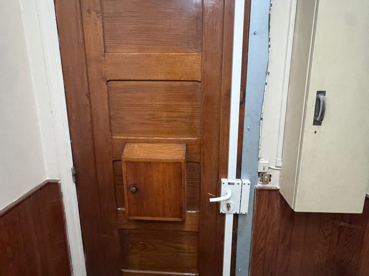 Serrure multipoints à tringle posée sur une porte ancienne en bois